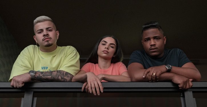 A Netflix divulgou imagens da 3ª temporada de Sintonia, que estreia dia 13 de julho no streaming. Mais maduros e enfrentando desafios cada vez maiores, os três amigos – Rita (Bruna Mascarenhas), Doni (Jottapê) e Nando (Christian Malheiros) - vão fazer altos “corres” para conquistar seus sonhos. Os novos episódios de Sintonia trazem planos ainda mais ambiciosos para a vida de cada um dos três jovens da Vila Áurea, bairro fictício em São Paulo: Rita se prepara para concorrer à vaga de vereadora pela congregação; Doni luta para se manter em evidência na música, depois de ter atingido o topo das paradas de funk; e Nando, que passou a ser um dos criminosos mais procurados do Brasil, questiona se vale a pena continuar no mundo do tráfico de drogas. Agora, o relacionamento deles custa caro - qualquer exposição pode arruinar suas carreiras e até levá-los à prisão. Produzida pela Gullane, Sintonia é baseada em uma ideia original de KondZilla e foi criada por KondZilla, Felipe Braga e Guilherme Quintella. A direção dos episódios é de Johnny Araújo, Daniela Carvalho e Gabriel Zerra, e a produção é de Caio Gullane e Fabiano Gullane. Veja as fotos: